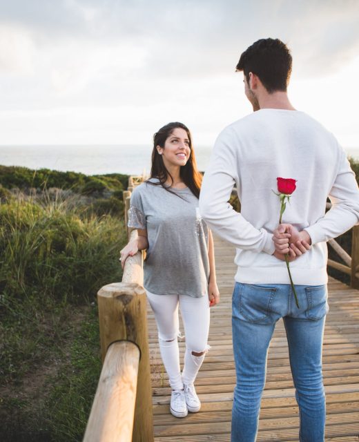 man-looking-his-girlfriend-while-hiding-rose-his-back